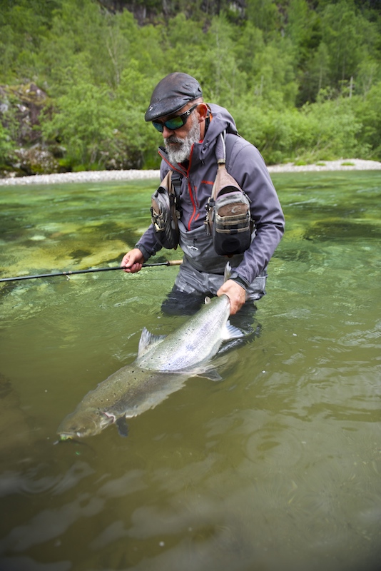 man in water holding onto large fish