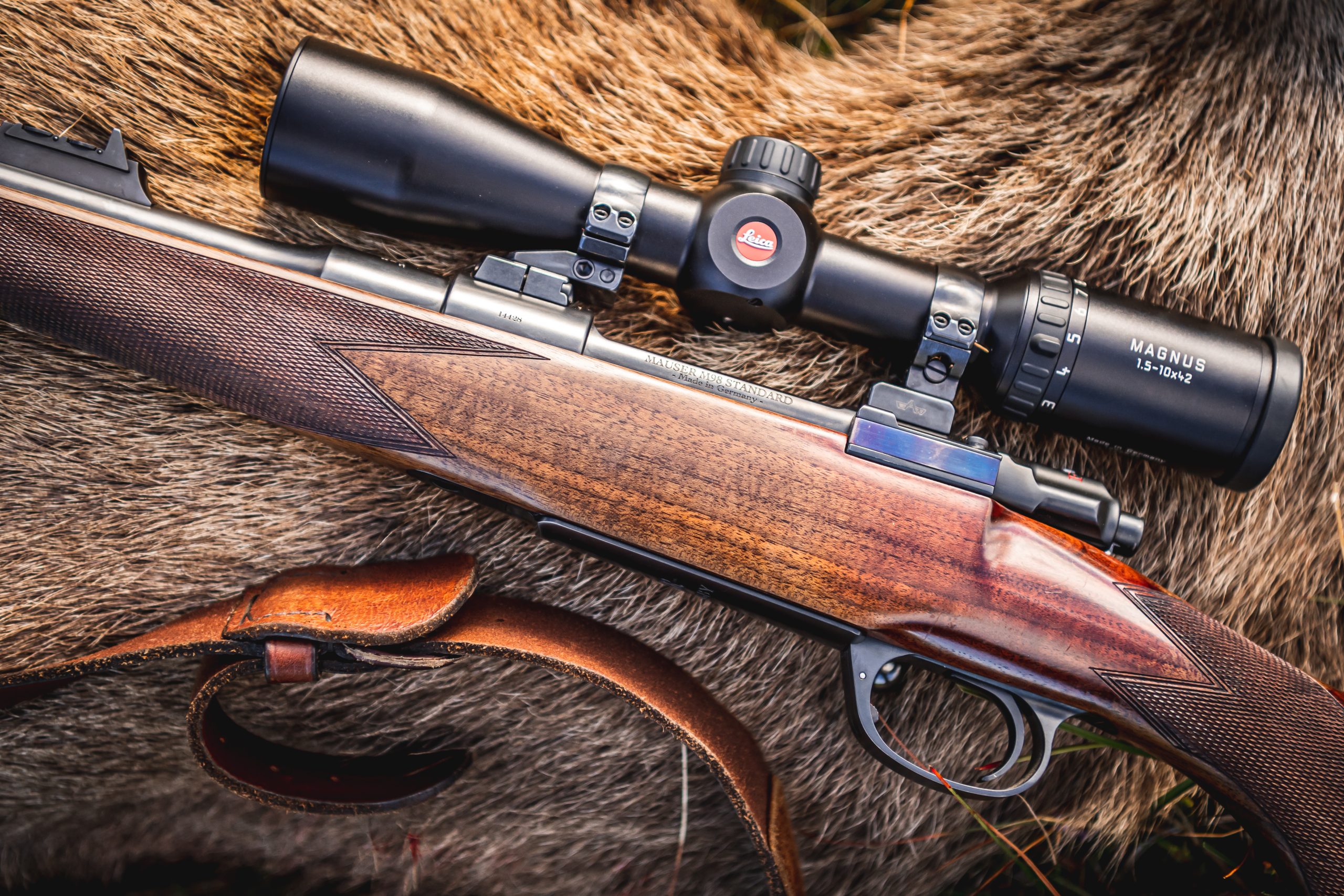 Rifle laying on hide of a red stag