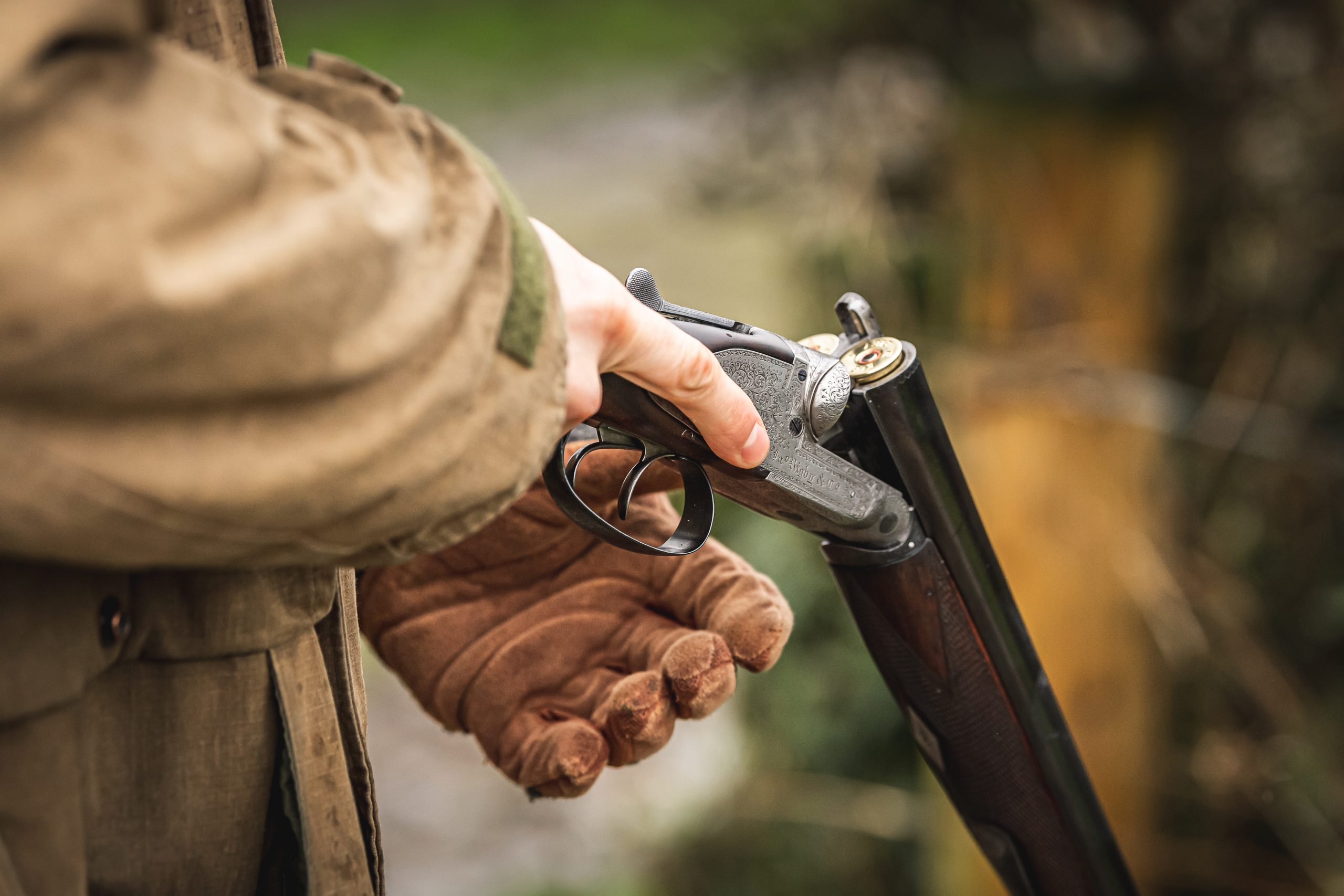 Man holding a side by side shotgun with cartridges in the chamber