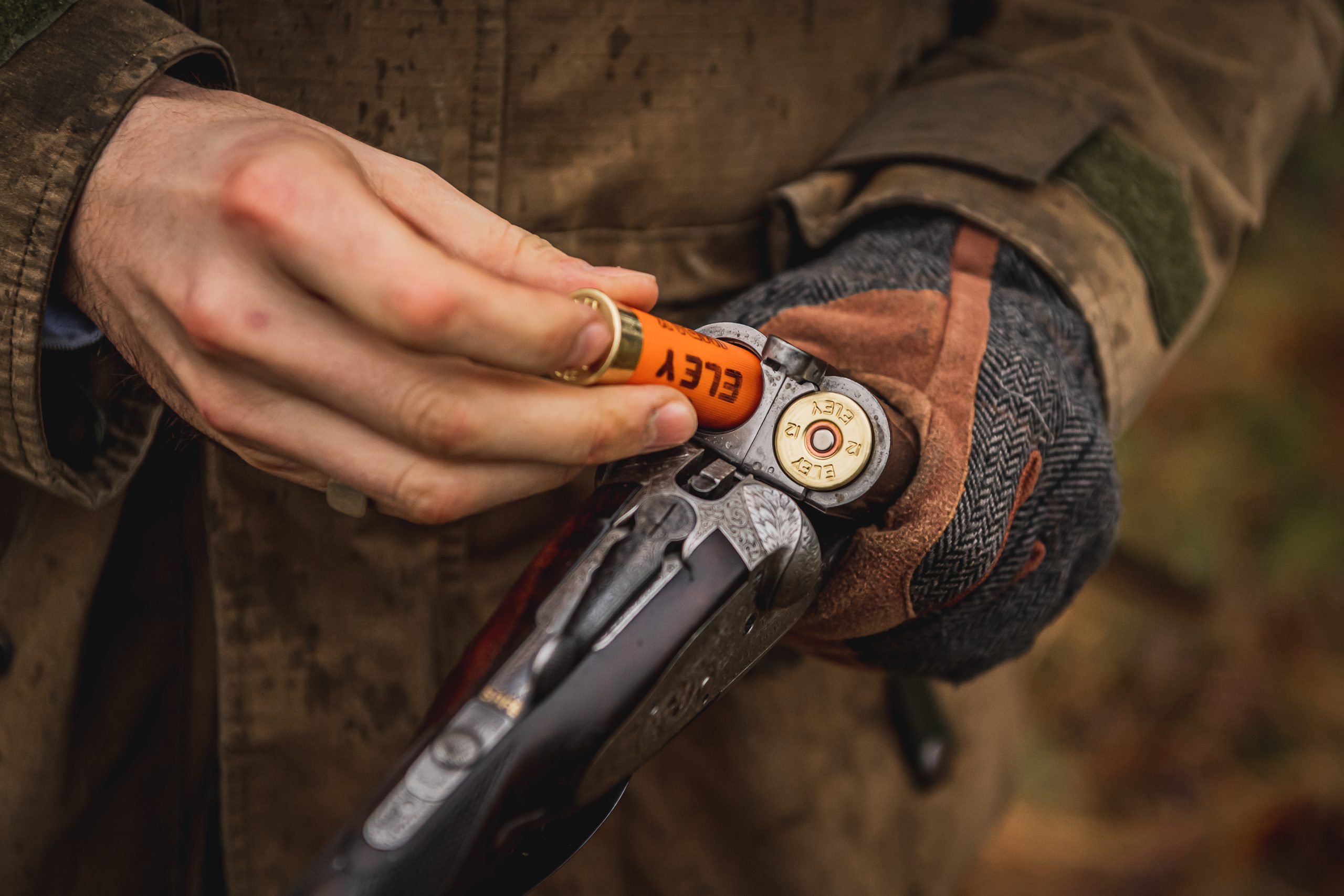 A man loading a game cartridge into a side by side shotgun