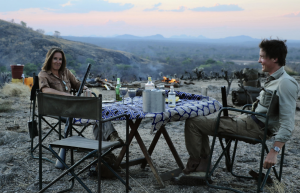 Katy and her friend sitting round a camping table filled with food