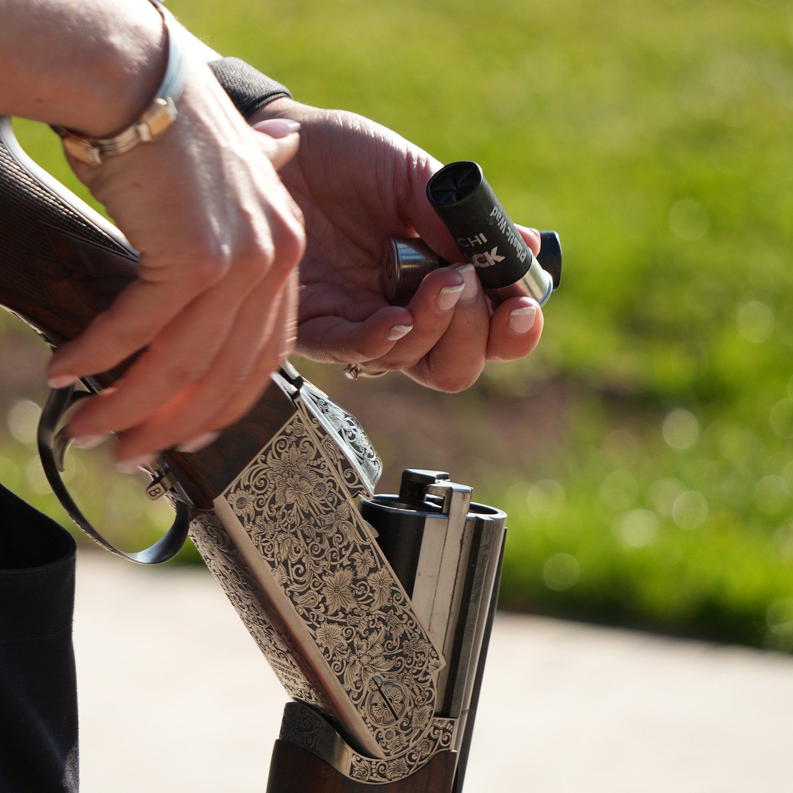 A Fiocchi FBLACK cartridge being loaded into an engraved side-by-side shotgun